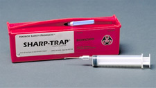 a syringe with needle next to a sharp trap box for storage