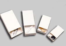 white paper boxes with sliding covers, open showing contents: razor blade, cigarette butts, and a button
