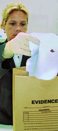 laboratory technician removing blood-stained evidence from sealed evidence bag.