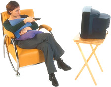 Imagen de una mujer sentada en un silln, viendo la televisin.