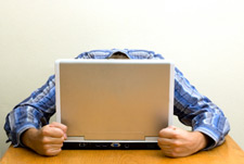 man at laptop with head on keyboard and clenched fists