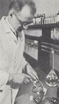 Calvin Goddard, working in a laboratory, examining a revolver.