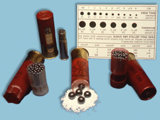 Shotshell and pellets of varying sizes, next to measuring chart.