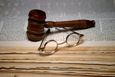 Image of a gavel, glasses and book.