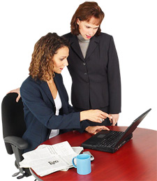 Image of two woman looking at laptop on table.
